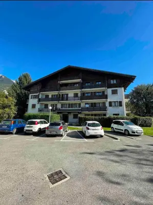 a building with cars parked in a parking lot at Studio La Vallée Blanche in Sallanches