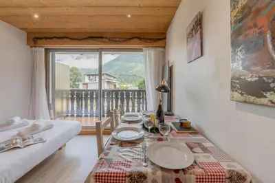 a bedroom with a bed and a table and a window at Clos Du Savoy - South Facing Balcony - Happy Rentals in Chamonix-Mont-Blanc