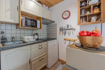 a red couch in a living room with a kitchen at Clos Du Savoy - South Facing Balcony - Happy Rentals in Chamonix-Mont-Blanc