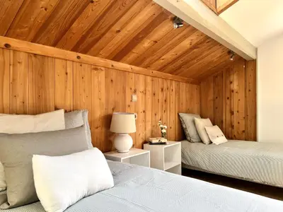 a bedroom with two beds and a wooden wall at Appartement Champêtre - Terrasse, Vue & Parking by AlpenlySallanches in Domancy