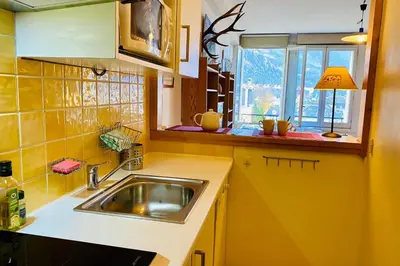 a yellow kitchen with a sink and a window at Alpine stay right in the center of Chamonix in Chamonix-Mont-Blanc