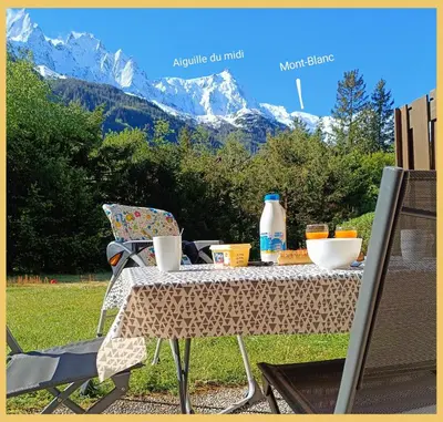 a table with food and drinks on it with a mountain at L'Aiguille de Chamonix I Appartement Les Praz in Chamonix-Mont-Blanc