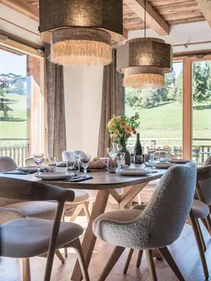 a dining room with a table and chairs and windows at Chalet Zazen I Le Chalet Club in Combloux