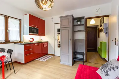 a kitchen and living room with red cabinets and a table at Les Sommets Studio in Chamonix-Mont-Blanc