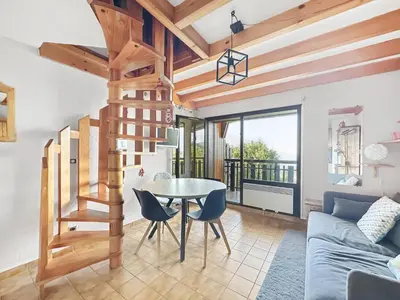 a living room with a table and a staircase at BA229 - 2 pieces mezzanine 6 pers pied de pistes in Les Carroz d'Araches