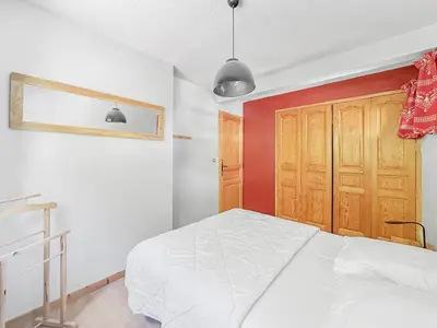 a bedroom with a white bed and a wooden door at BA229 - 2 pieces mezzanine 6 pers pied de pistes in Les Carroz d'Araches