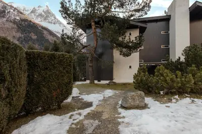 a house with snow on the ground in front of a mountain at Quartz - Appt 4 etoiles vue Mont-Blanc - Centre in Chamonix-Mont-Blanc
