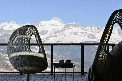 two chairs and a table on a balcony with snow covered mountains at JAMES TAMG31 - luxury design chalet Megeve in Combloux