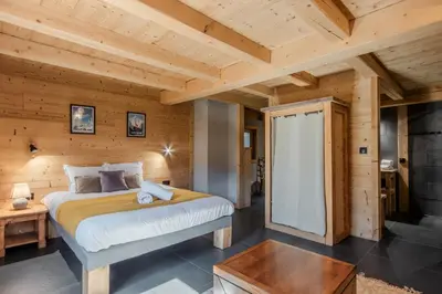 a bedroom with a bed and a wooden wall at Appt Vincent - 200 m2 - Ideal famille - Vue Mont-B in Cordon