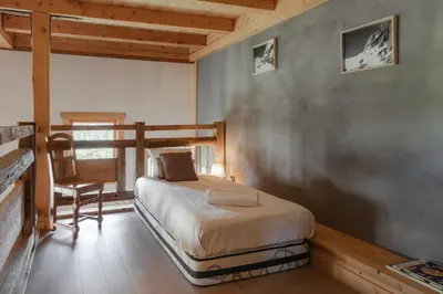 a bedroom with a bed and a chair in a room at Appt Vincent - 200 m2 - Ideal famille - Vue Mont-B in Cordon