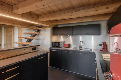 a kitchen with black cabinets and a sink and a ladder at Appt Vincent - 200 m2 - Ideal famille - Vue Mont-B in Cordon