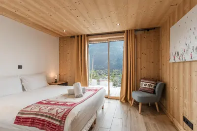 a bedroom with a bed and a chair and a window at Chalet La Source - Ideal familles ski et rando in Chamonix-Mont-Blanc