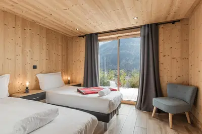 a room with two beds and a chair and a window at Chalet La Source - Ideal familles ski et rando in Chamonix-Mont-Blanc