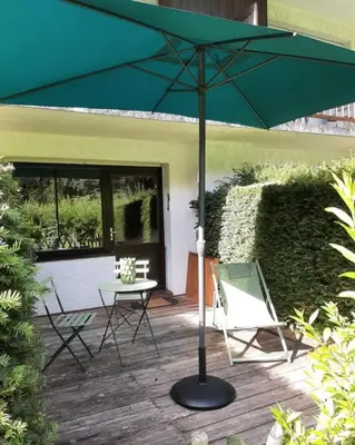 a green umbrella on a patio with a table and chairs at Le Roffie-lan in Les Contamines-Montjoie