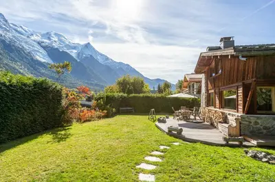 a house with a garden and mountains in the background at Chalet Martinique - Chamonix All Year in Chamonix-Mont-Blanc
