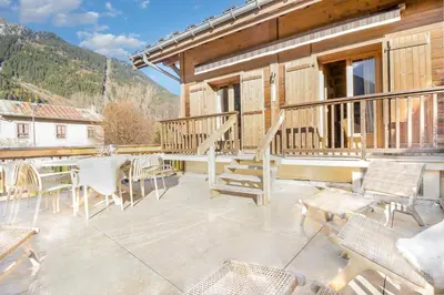 a balcony with a table and chairs and mountains at Chalet Scandinave - Ski-in out Piste Flegere - Next to Golf - By Cozee Rentals in Chamonix-Mont-Blanc