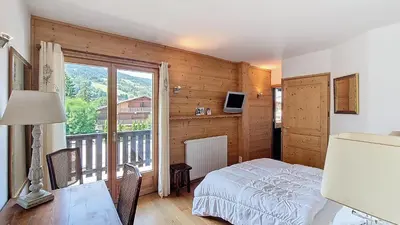a bedroom with a bed and a view of a balcony at 1 Peupliers - CENTRE du VILLAGE - in Megève