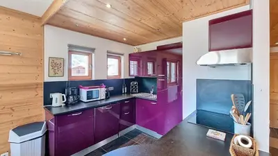 a kitchen with purple cabinets and a wooden ceiling at 1 Peupliers - CENTRE du VILLAGE - in Megève
