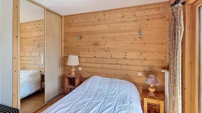 a bedroom with wooden walls and a bed and a mirror at 1 Peupliers - CENTRE du VILLAGE - in Megève