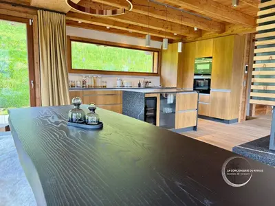 a large kitchen with a large black counter top at Chalet neuf La Marmotière - Vue sur la Montagne in Combloux