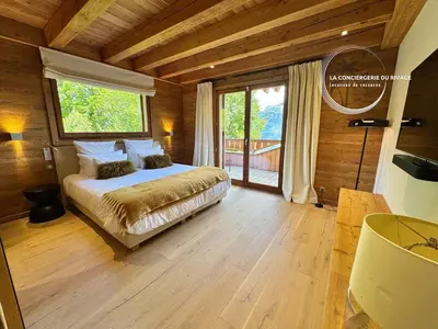 a bedroom with a bed and a large window at Chalet neuf La Marmotière - Vue sur la Montagne in Combloux