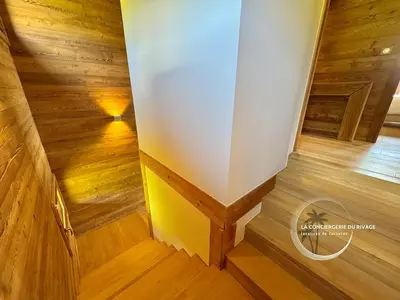a staircase in a house with wood floors and a wall at Chalet neuf La Marmotière - Vue sur la Montagne in Combloux