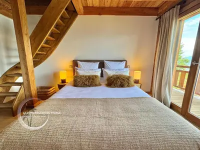 a bedroom with a large bed with two pillows at Chalet neuf La Marmotière - Vue sur la Montagne in Combloux