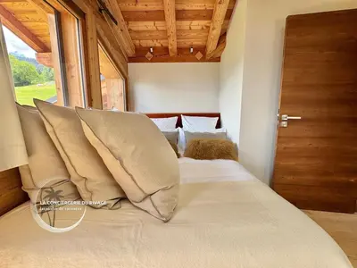 a bedroom with a bed with pillows and a window at Chalet neuf La Marmotière - Vue sur la Montagne in Combloux