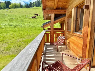 a porch of a house with two chairs and a field at Chalet neuf La Marmotière - Vue sur la Montagne in Combloux