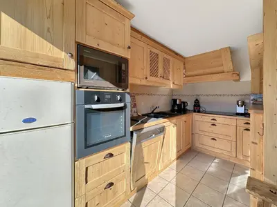 a kitchen with wooden cabinets and a white refrigerator at PE317 - 4 pieces 6 a 7 pers proximite centre in Les Carroz d'Araches