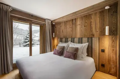 a bedroom with a white bed and a window at Luxury Chalet Black Mountain - 4BR, Sleeps 10, Fireplace, Mountain Views & Garden - Megève in Megève