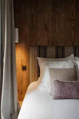a bed with white pillows and a wooden headboard at Luxury Chalet Black Mountain - 4BR, Sleeps 10, Fireplace, Mountain Views & Garden - Megève in Megève