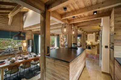 a kitchen and dining room with wooden walls and a table and chairs at Luxury Chalet Black Mountain - 4BR, Sleeps 10, Fireplace, Mountain Views & Garden - Megève in Megève