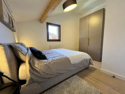 a bedroom with a bed and a couch and a window at Duplex élégant au centre, vue vallée, confort moderne - FR-1-624-185 in Samoëns