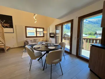 a dining room and living room with a table and chairs at Duplex élégant au centre, vue vallée, confort moderne - FR-1-624-185 in Samoëns