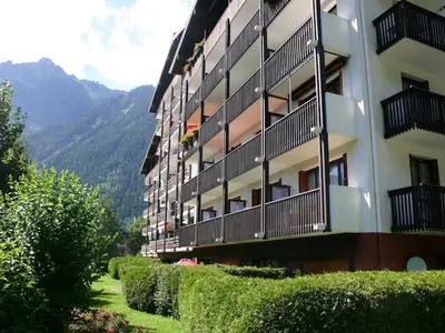 a building with balconies and bushes next to a mountain at Résidence Les Periades - Chamonix in Chamonix-Mont-Blanc