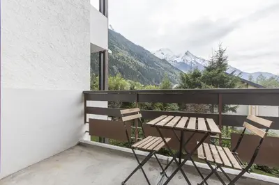a balcony with a table and chairs and mountains at Résidence Les Periades - Chamonix in Chamonix-Mont-Blanc