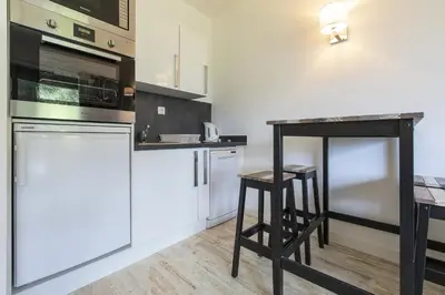 a kitchen with white appliances and a table and stool at Résidence du Brévent - Chamonix Village in Chamonix-Mont-Blanc