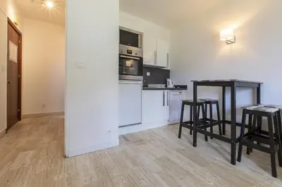 a kitchen with two bar stools and a table at Résidence du Brévent - Chamonix Village in Chamonix-Mont-Blanc