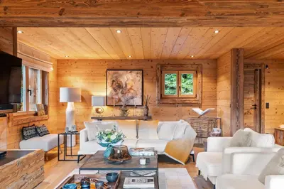 a living room with white furniture and wooden walls at Chalet Ysalpe - Vue montagne hammam sauna jacuzzi et salle cinéma in Megève