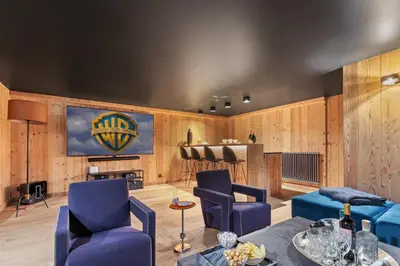 a living room with blue chairs and a bar at Chalet Ysalpe - Vue montagne hammam sauna jacuzzi et salle cinéma in Megève