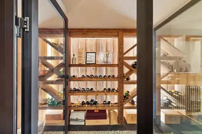 a room with a glass door and shelves with wine bottles at Chalet Ysalpe - Vue montagne hammam sauna jacuzzi et salle cinéma in Megève