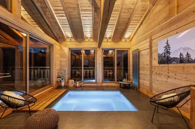 a pool in a room with two chairs and a table at Chalet Ysalpe - Vue montagne hammam sauna jacuzzi et salle cinéma in Megève
