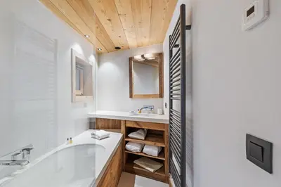 a bathroom with a tub and a sink and a mirror at Chalet Ysalpe - Vue montagne hammam sauna jacuzzi et salle cinéma in Megève
