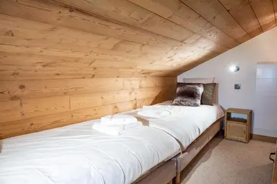 a large white bed in a room with wooden walls at Cozy Chalet 3BR 6P with Balcony – Megève in Megève
