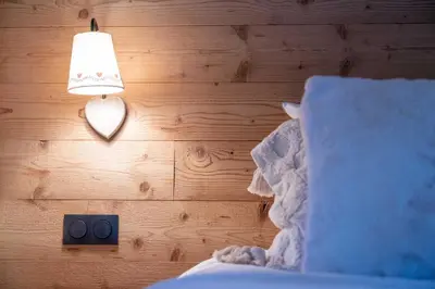 a bedroom with a lamp and a wooden wall at Cozy Chalet 3BR 6P with Balcony – Megève in Megève