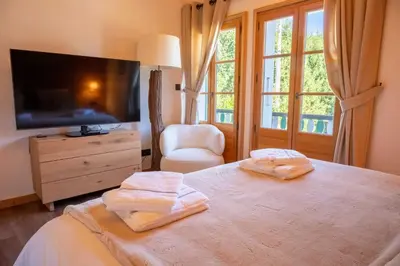 a bedroom with a bed with a television and a chair at Cozy Chalet 3BR 6P with Balcony – Megève in Megève