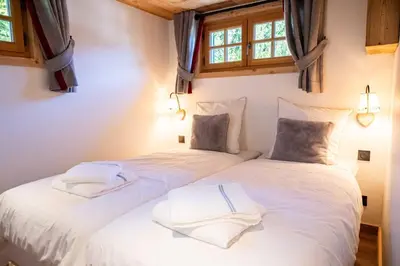 two beds in a bedroom with white sheets and windows at Cozy Chalet 3BR 6P with Balcony – Megève in Megève