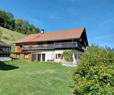 a large house with a brown roof and a yard at La Ferme De Réjane in Saint-Gervais-les-Bains