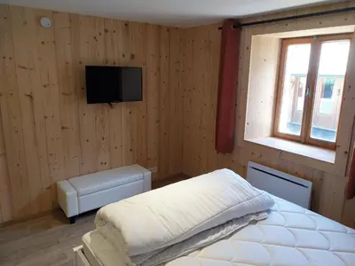 a bedroom with a bed and a television on a wall at La Ferme De Réjane in Saint-Gervais-les-Bains